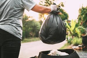 hand holding garbage black bag putting in to trash photo