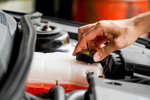 mechanic inspects the expansion tank with pink antifreeze. Vehicle coolant level in the car's radiator system. auto parts photo