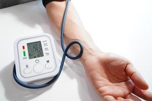Monitoreo de la presión arterial de los pacientes que usan un monitor de presión arterial en la parte superior del brazo en la sala de examen de la clínica. foto