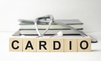 The word CARDIO is written on wooden cubes near a stethoscope on a wooden background. Medical concept photo
