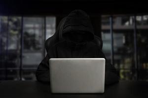 Hacker using computer with digital interface while sitting at desk of blurry interior. photo