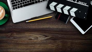 office stuff with Movie clapper, laptop, smartphone, tablet, coffee cup, pen, notepad and documents on the wood table photo