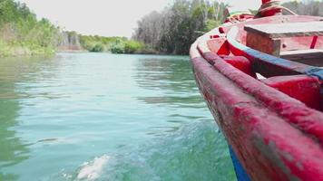 parte de un bote a motor rojo que parece un pequeño bote de pesca de los aldeanos. navegar sobre el agua para adentrarse en el mar y los bosques de manglares