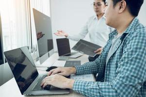 dos desarrolladores de software están analizando juntos el código escrito en el programa en la computadora en la sala de oficinas.