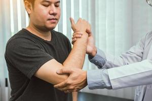Los fisioterapeutas asiáticos revisan los codos de los pacientes que se han sometido a rehabilitación ortopédica.