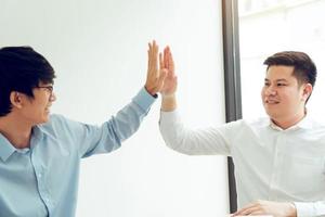 Two businessmen high five as they agree on the company's budget. photo