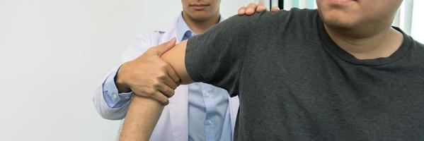 los fisioterapeutas presionan el hombro del paciente para comprobar si hay dolor.
