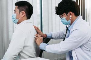 el médico asiático está usando un estetoscopio para escuchar los latidos del corazón del paciente. foto