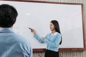 joven profesor asiático enseñando a los estudiantes en el aula. foto