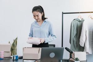 Asian entrepreneur is preparing her clothes that can be sold in paper boxes for delivery to customers. photo