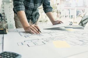 Interior designer or architect reviewing blueprints and holding pencil drawing on desk at home office. photo