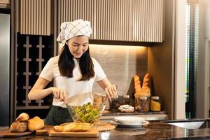 Asian housewife preparing fresh vegetables to make salad at home kitchen counter. photo