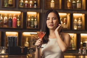 Asian women drinking cocktails and having fun at the bar at night. photo