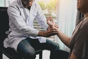 el fisioterapeuta revisa la muñeca del paciente presionando el hueso de la muñeca en la sala de la clínica. foto