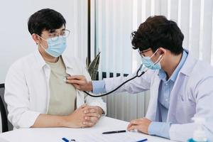 Asian doctor is using a stethoscope listen to the heartbeat of the patient. photo