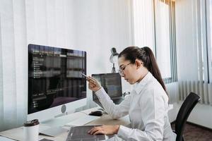 los desarrolladores de software están analizando el código escrito en el programa en la computadora en la sala de oficina.