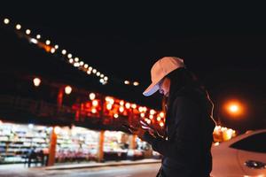 Asian adult woman using mobile phone  for call taxi at night. photo