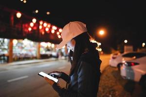 mujer adulta asiática usando teléfono móvil para llamar a un taxi por la noche. foto