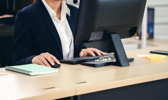 salario de mujer asiática de mano de negocios usando mouse y computadora. foto