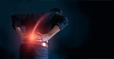hombre que sufre de dolor de espalda por causa del síndrome de la oficina, sus manos tocan la parte inferior de la espalda. concepto médico y de salud