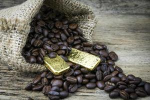 Coffee beans and Gold Bullion in sackcloth bag on wooden background photo