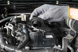 A mechanic is opening the oil cap from a car engine. photo