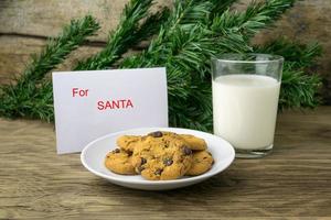 galletas y un vaso con leche con una nota blanca para santa foto