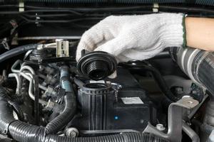 Un mecánico está abriendo el tapón de aceite del motor de un automóvil. foto