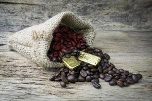 Coffee beans and Gold Bullion in sackcloth bag on wooden background photo