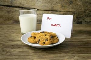 galletas y un vaso con leche con una nota blanca para santa foto