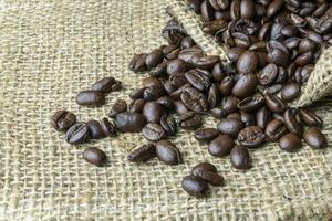 Coffee beans in sackcloth bag on wooden background photo