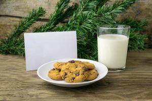 galletas y un vaso con leche con una nota blanca para santa foto