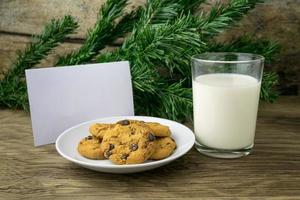 galletas y un vaso con leche con una nota blanca para santa foto