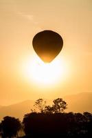 la silueta del globo aerostático volando en el cielo durante la vista del atardecer.