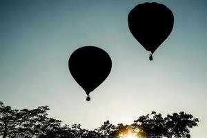 la silueta de globos aerostáticos volando en el cielo por la noche. foto