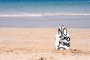 señal de advertencia de no fumar en la tabla de surf blanca en la playa en verano, concepto de diseño de protección ambiental del mar, espacio de copia, estilo de vida.