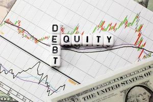 Debt and equity letter cube on white candle stick chart and dollar background. conceptual image for DE ratio in stock investment. photo