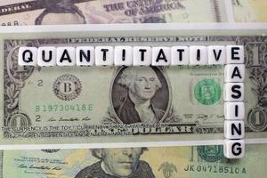 Quantitative Easing written on white cube with dollars background for QE concept. photo