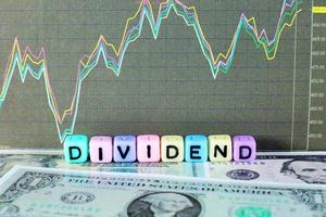 Conceptual image of the word dividend on letter cube with stock graph and dollar background. photo