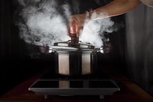 hand holding of metal pot cover with hot steam flowing from inside photo