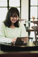 mujer joven asiática leyendo un mensaje en una tableta de computadora con cara sonriente