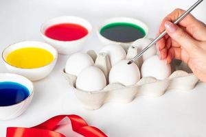 Young woman paints white eggs for easter. photo