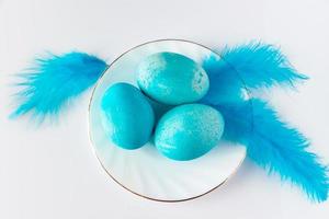 Composition of blue easter eggs and feathers on a light background.