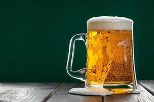 Beer is poured out of glass. Mug with traditional Irish ale on a dark background. photo