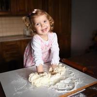 pretty little girl having fun kneads dough photo