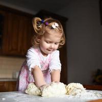 pretty little girl having fun kneads dough photo