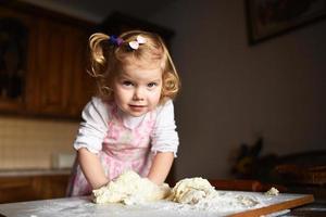 pretty little girl having fun kneads dough photo