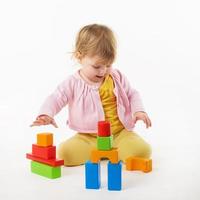 little girl playing with colorful toy blocks