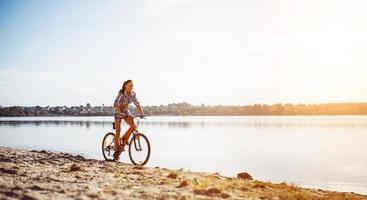 mujer en bicicleta cerca del agua foto