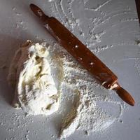 Wooden rolling pin with white wheat flour on the table photo